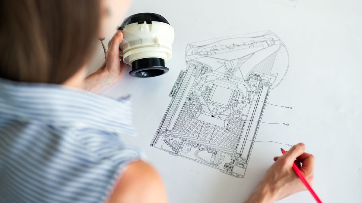 Engineer working on a custom PMDC motor design with a technical drawing and motor component